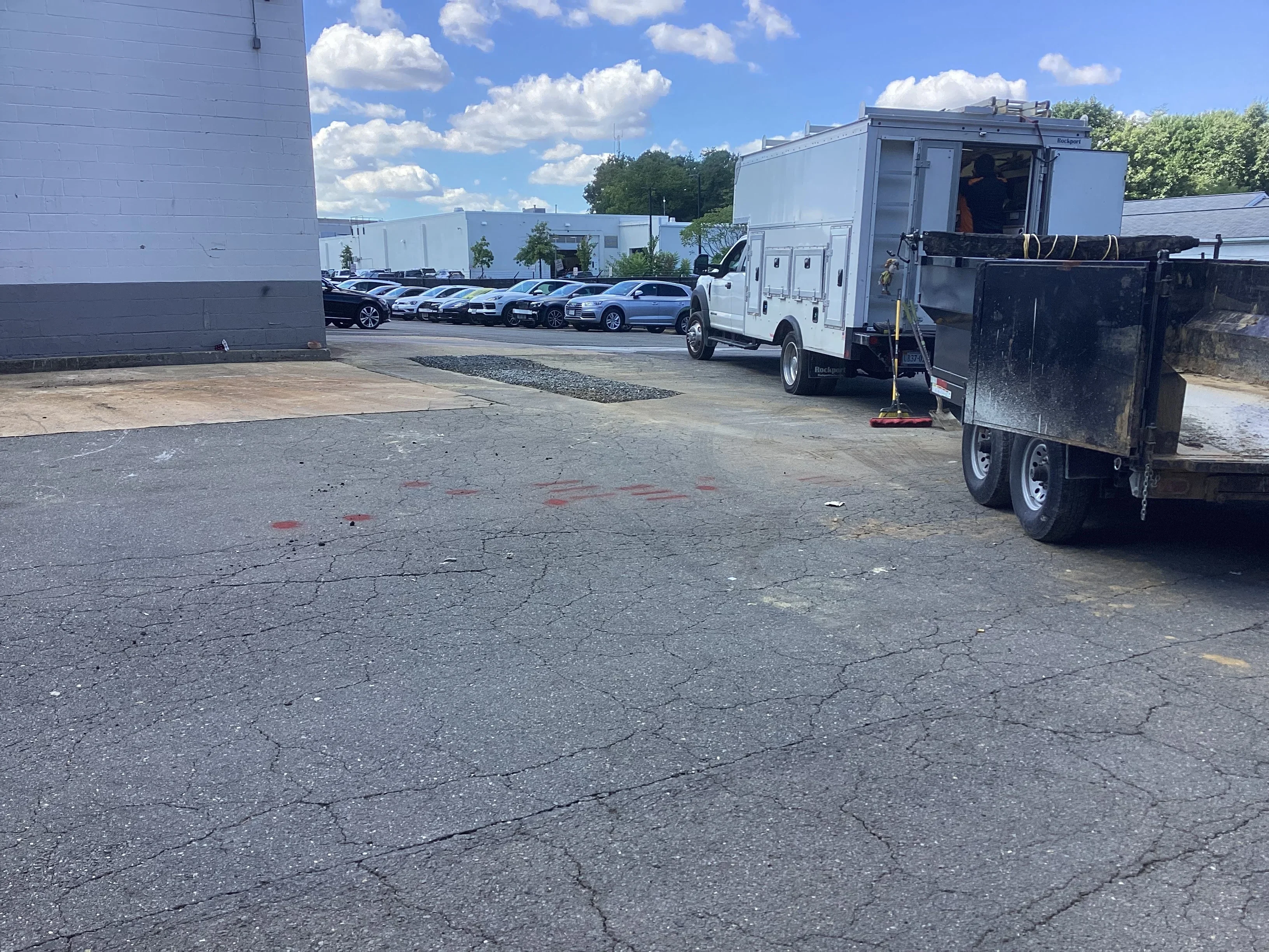 Commercial parking lot excavation with utility trucks and marked underground work area