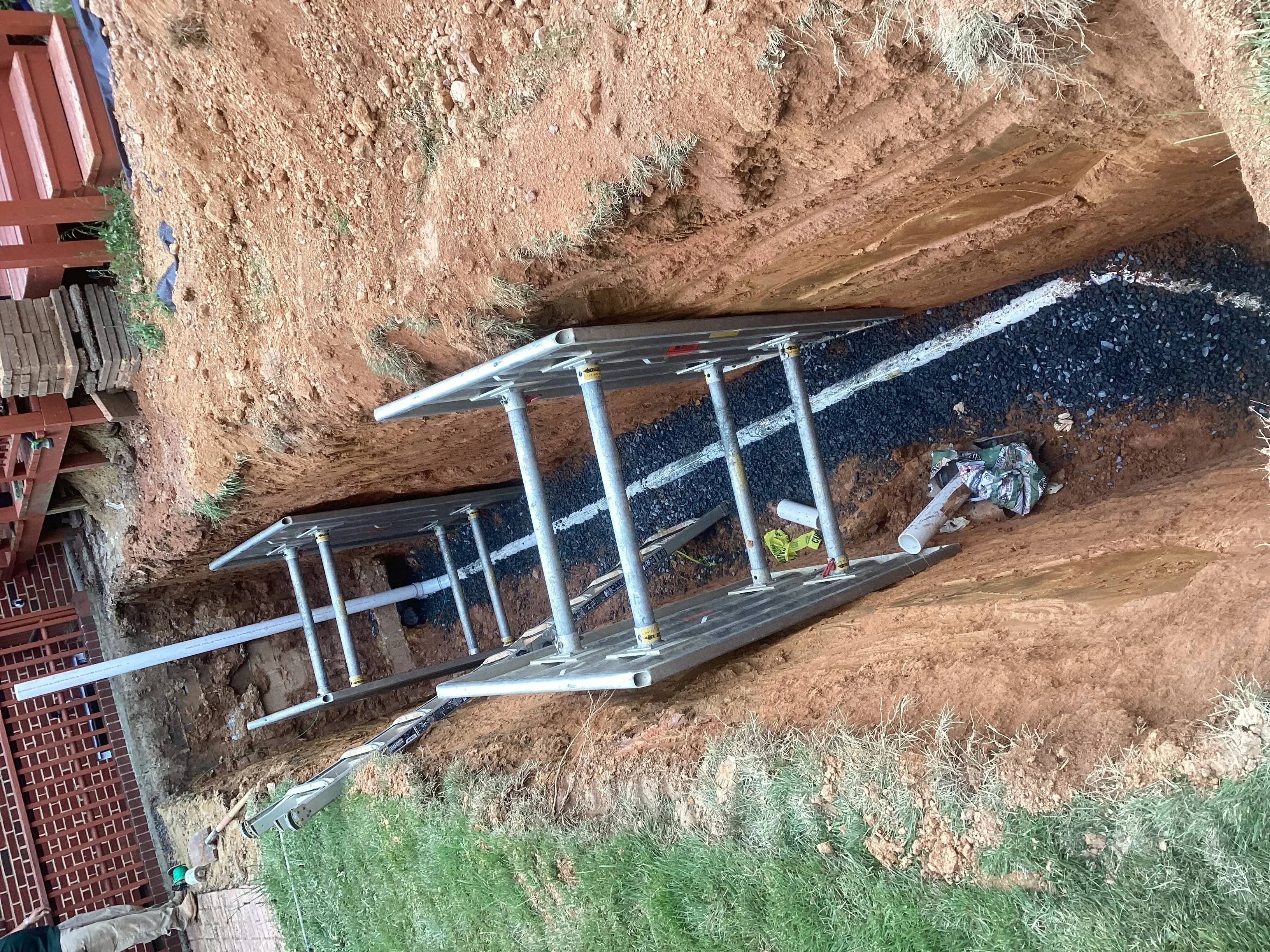 Underground drainage pipes with gravel bedding installed in excavated trench