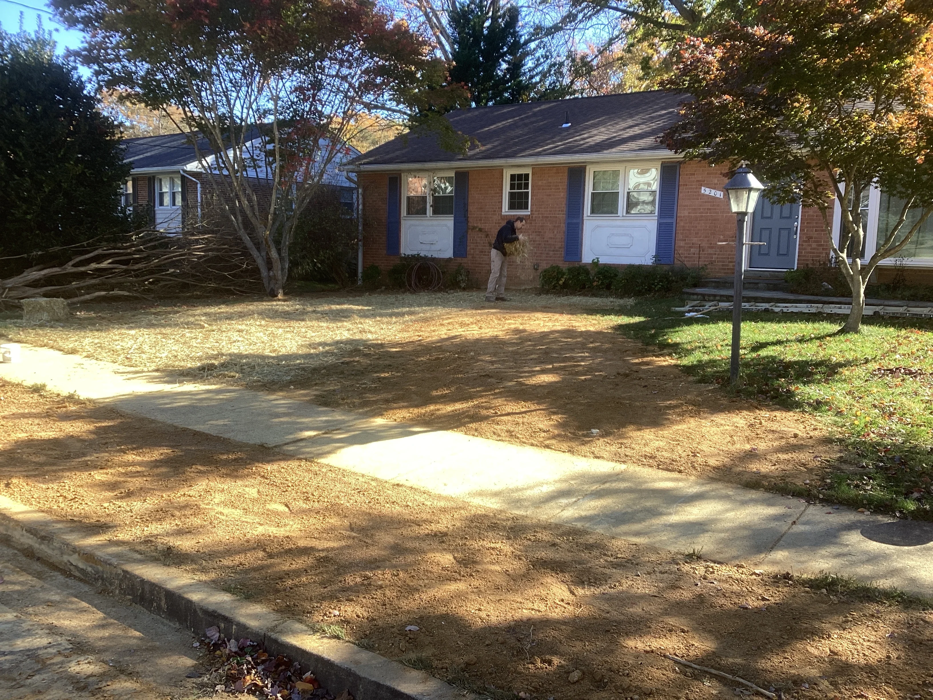 Brick home with excavated yard showing graded soil and concrete walkways