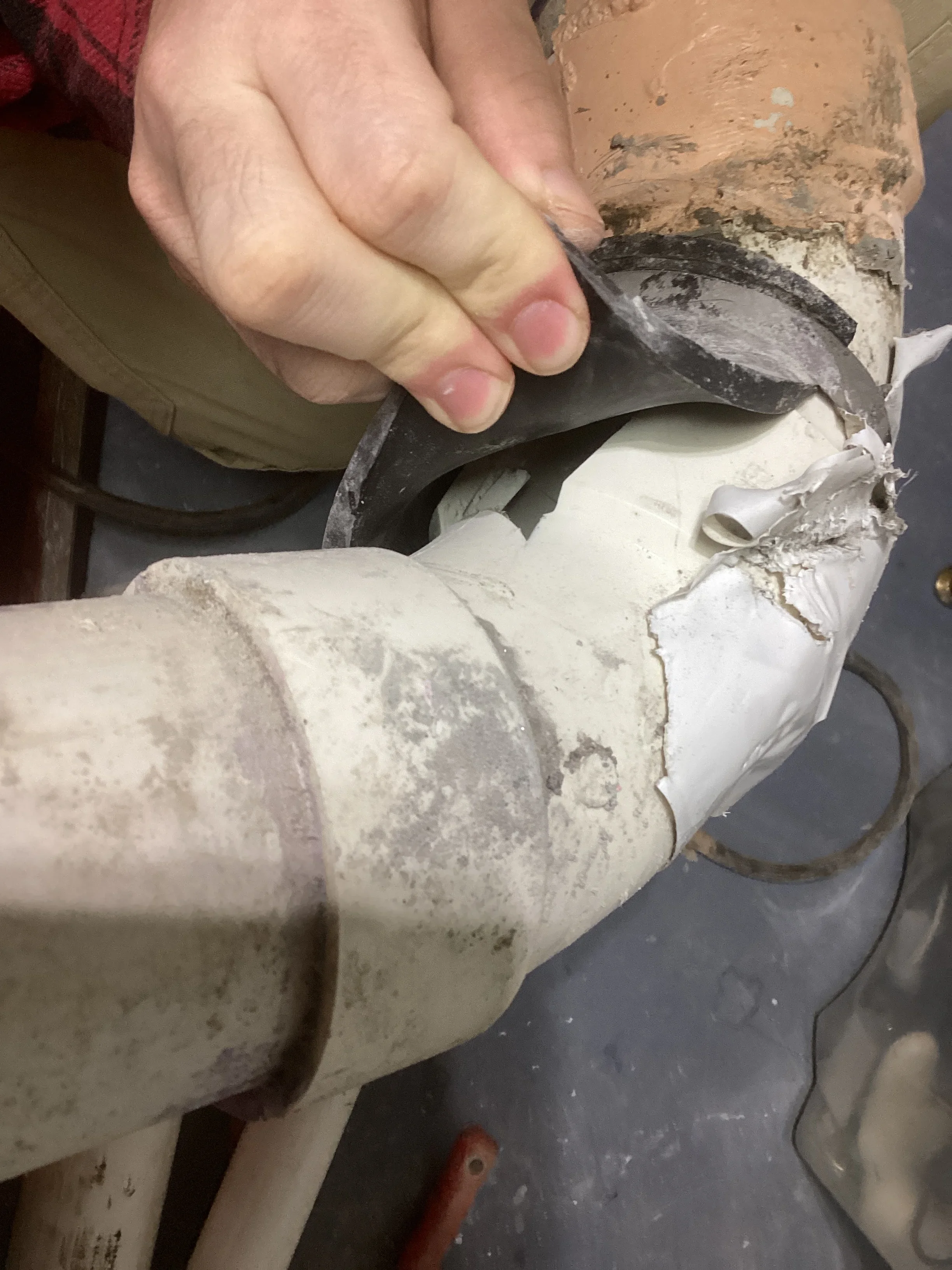 Technician sealing PVC pipe joint with white coupling and compound material