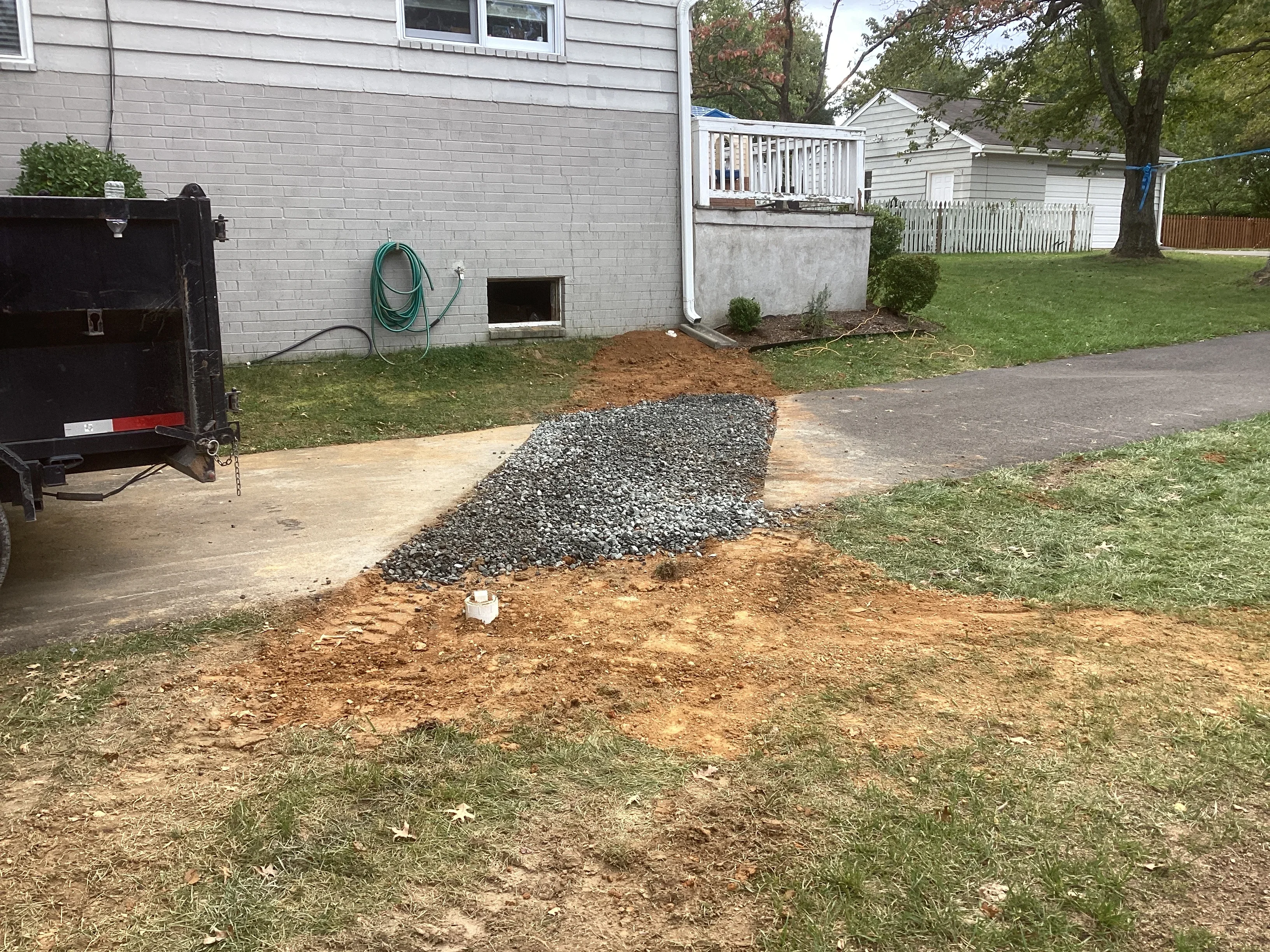 Residential drainage installation with gravel base and grading work near foundation