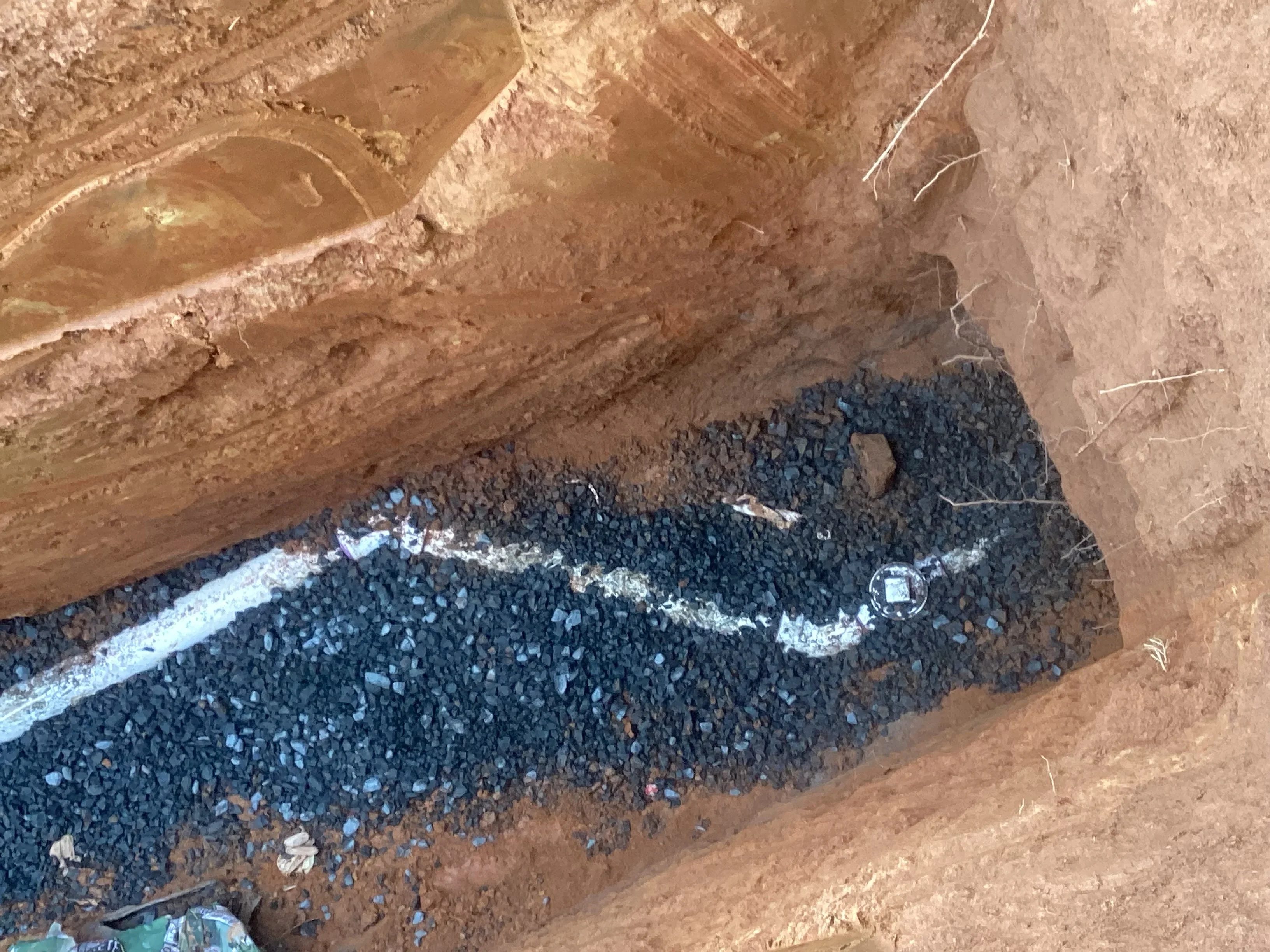 Underground PVC sewer pipe installation with stone bedding in excavated trench
