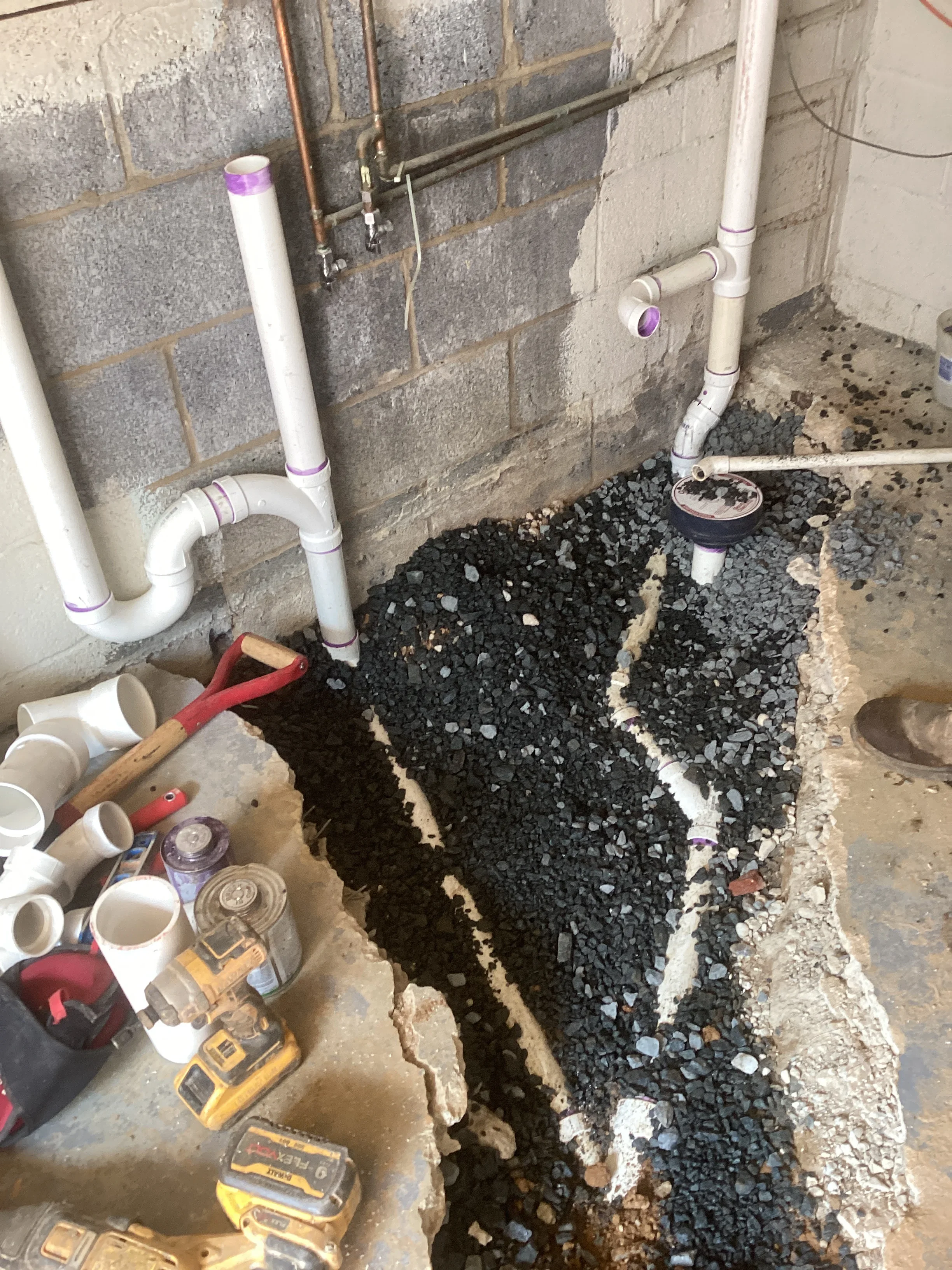 PVC drainage pipes installed in basement with gravel base and stone foundation preparation