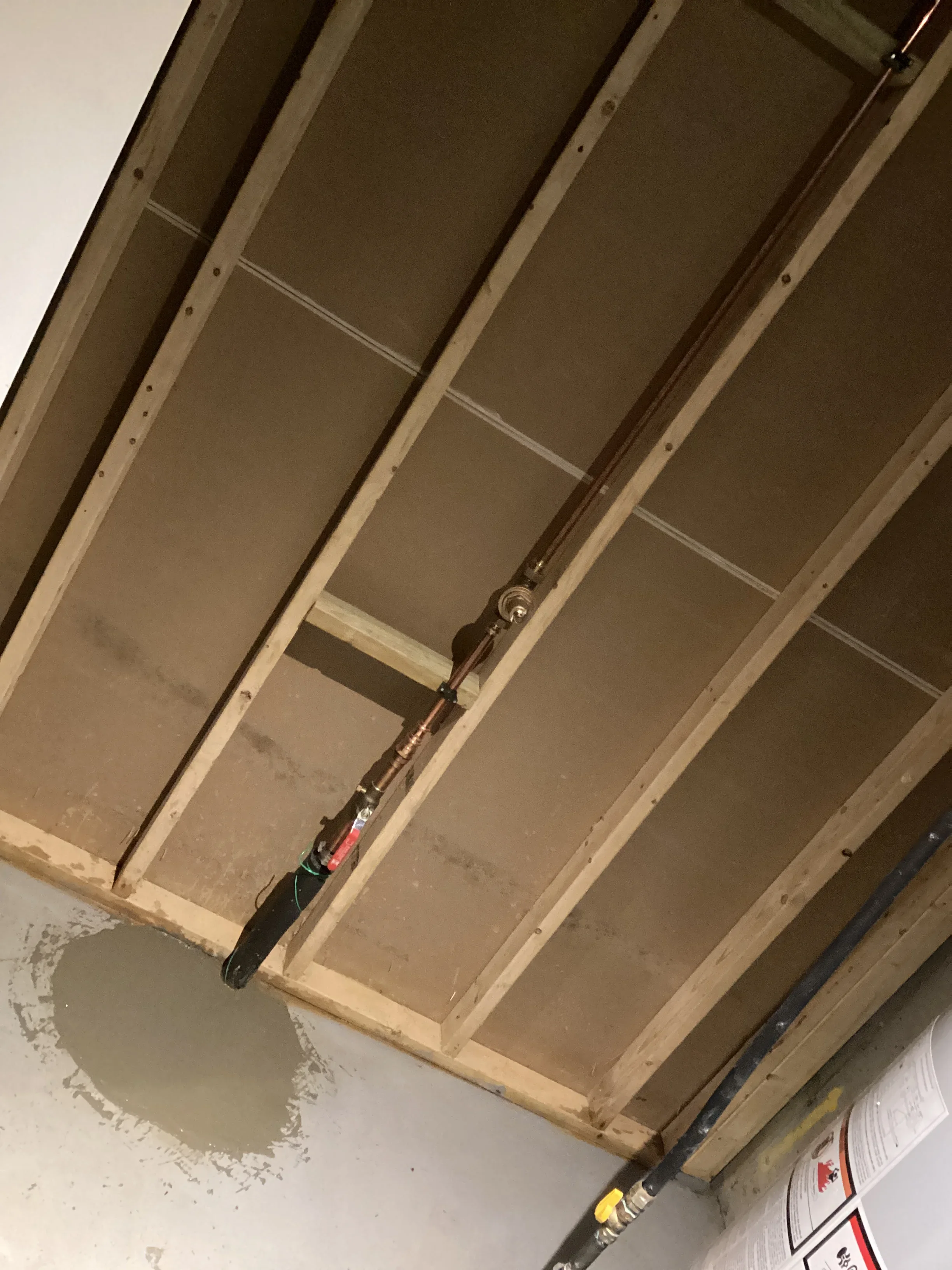 Overhead plumbing rough-in with copper and PEX lines attached to wooden ceiling joists