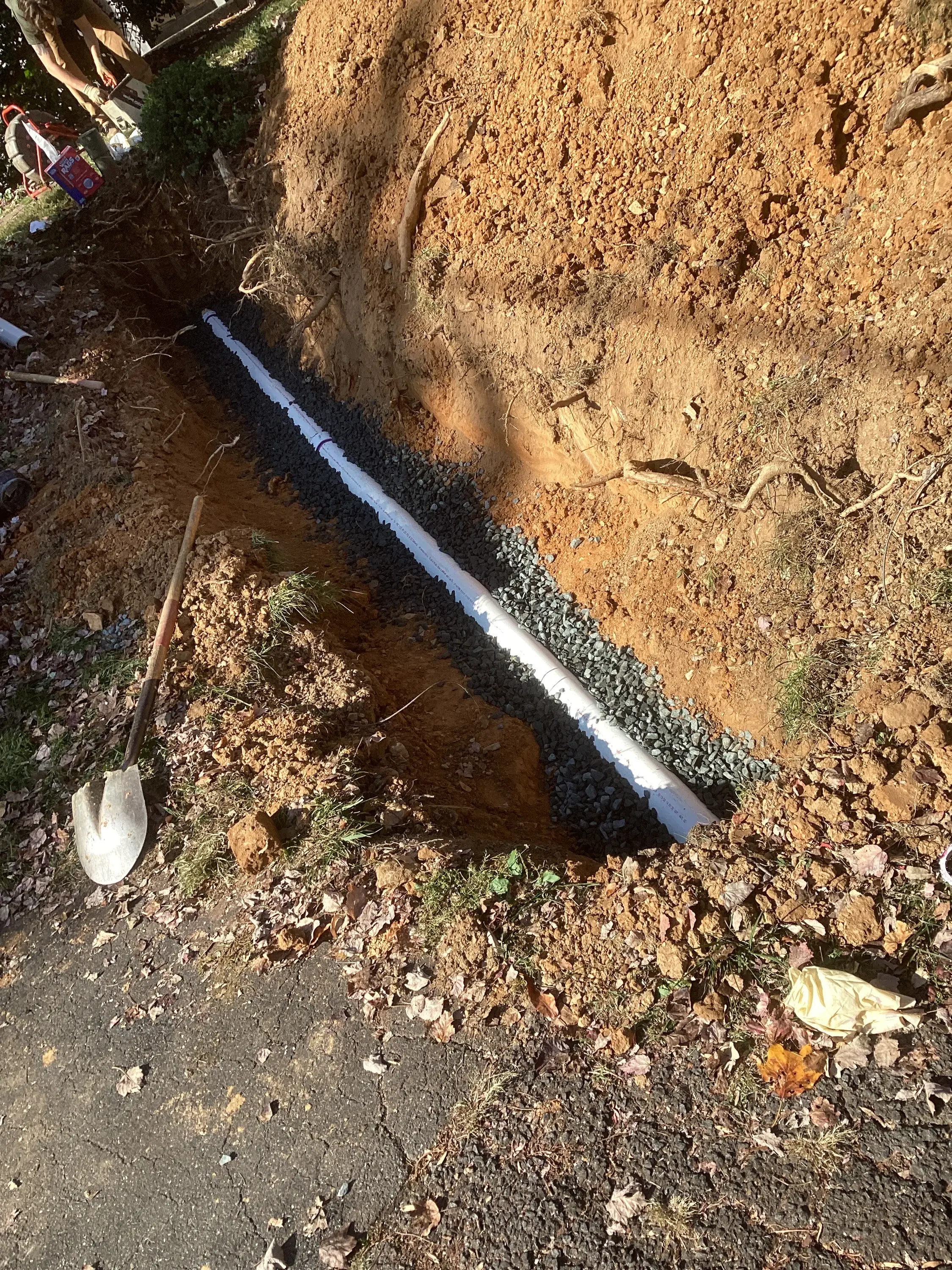 Underground drainage pipe installation in trench with gravel bedding and proper slope