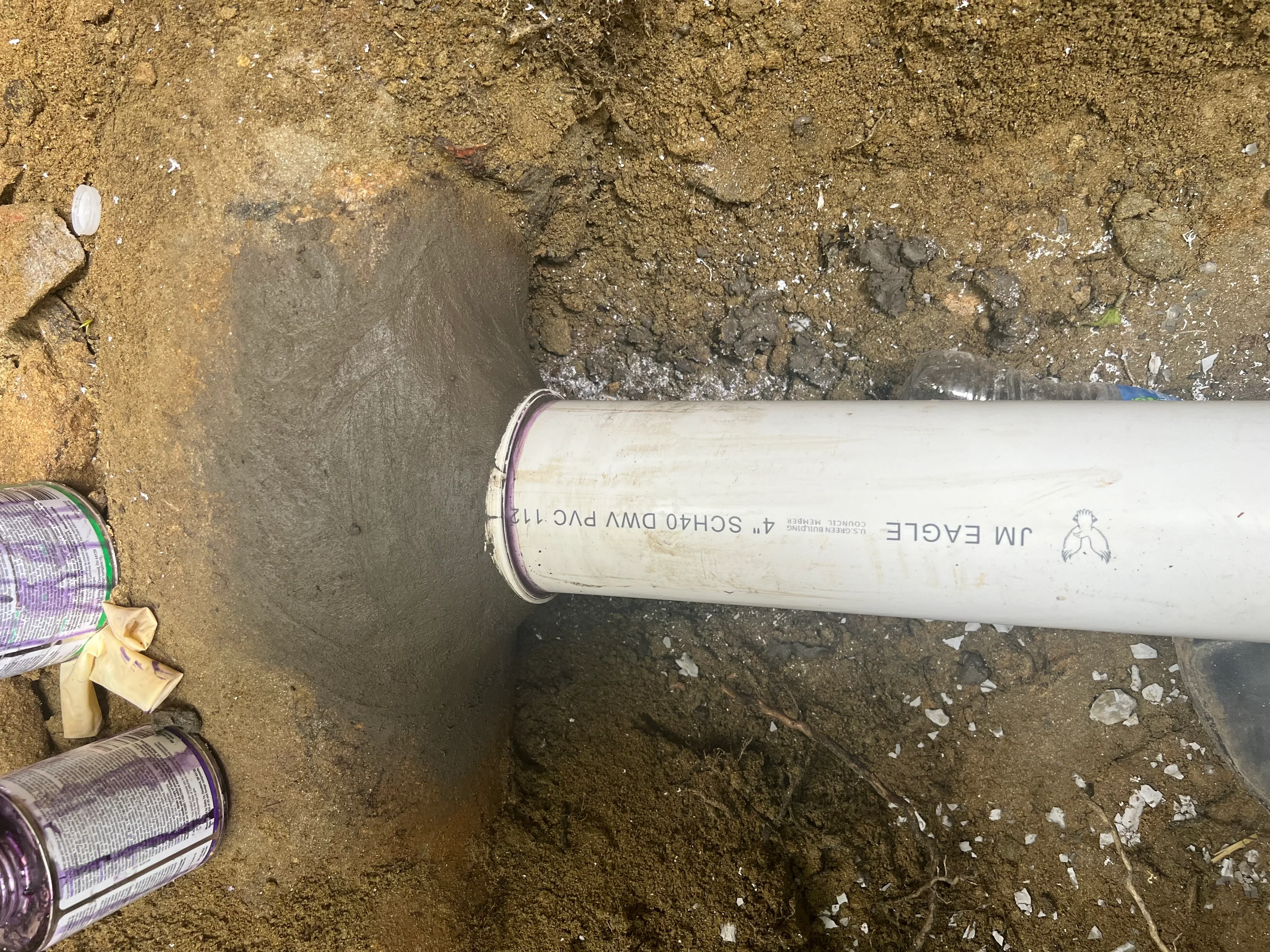 White 4-inch PVC sewer pipe installed in underground trench with soil excavation