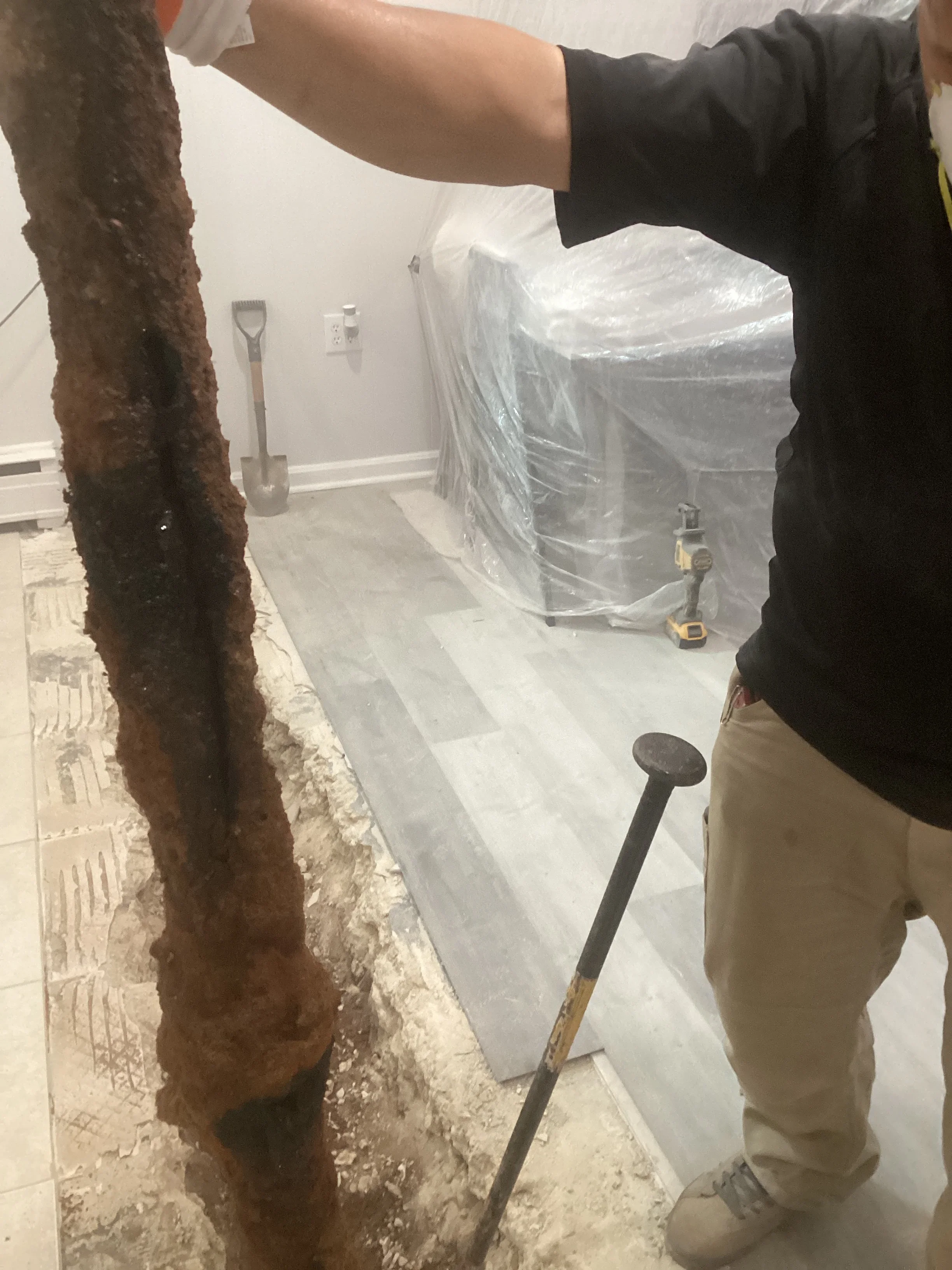 Technician removing corroded cast iron drain pipe from basement during plumbing renovation