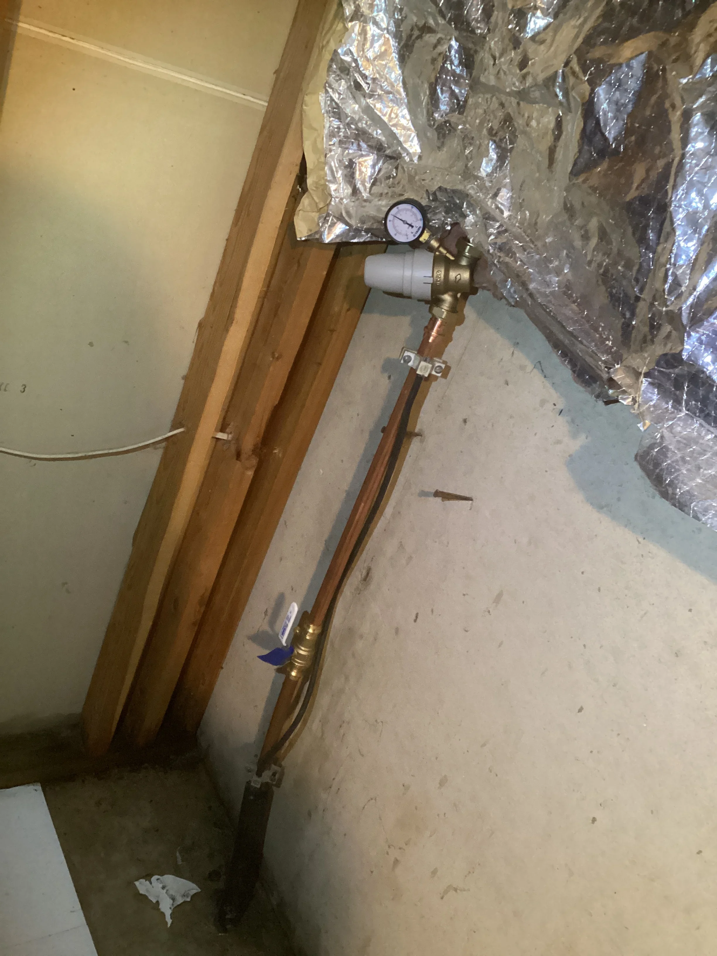 Copper radiant floor heating tubing with pressure gauge and control valve installed in subfloor