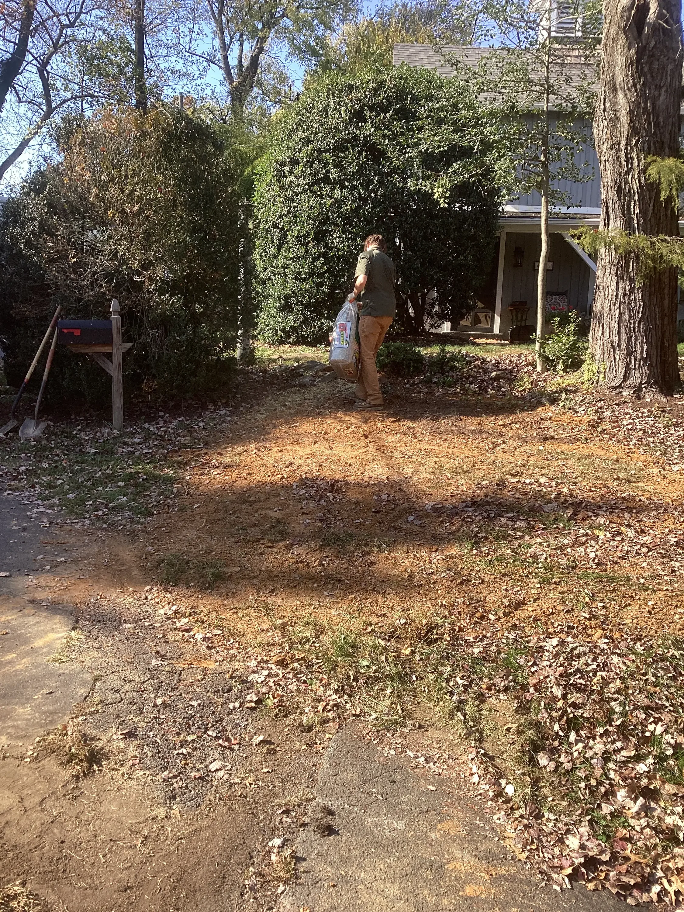 Residential driveway excavation with gravel base and mature hedges surrounding property