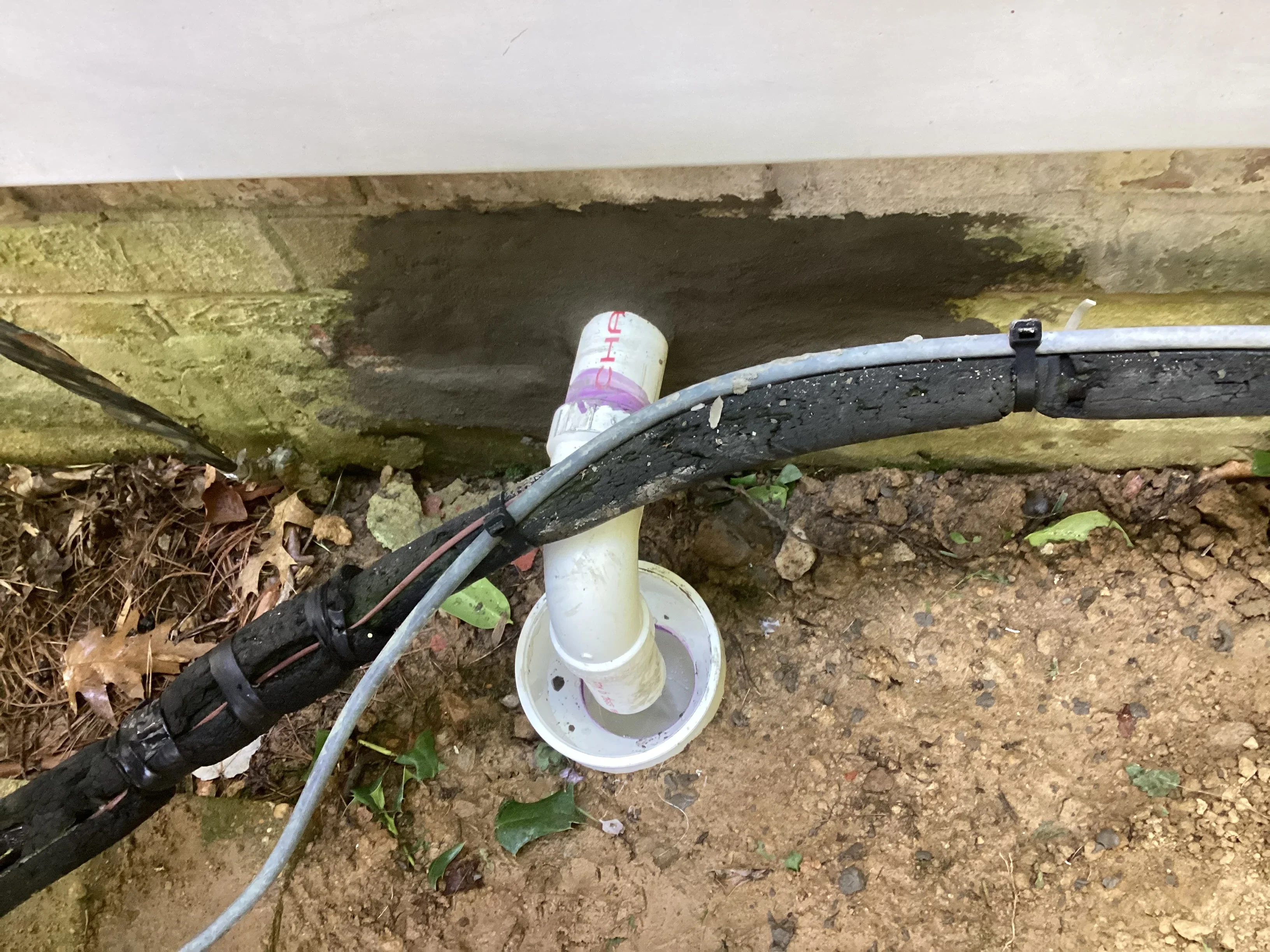 Underground sewer pipe repair with exposed drainage line and inspection equipment at excavation site