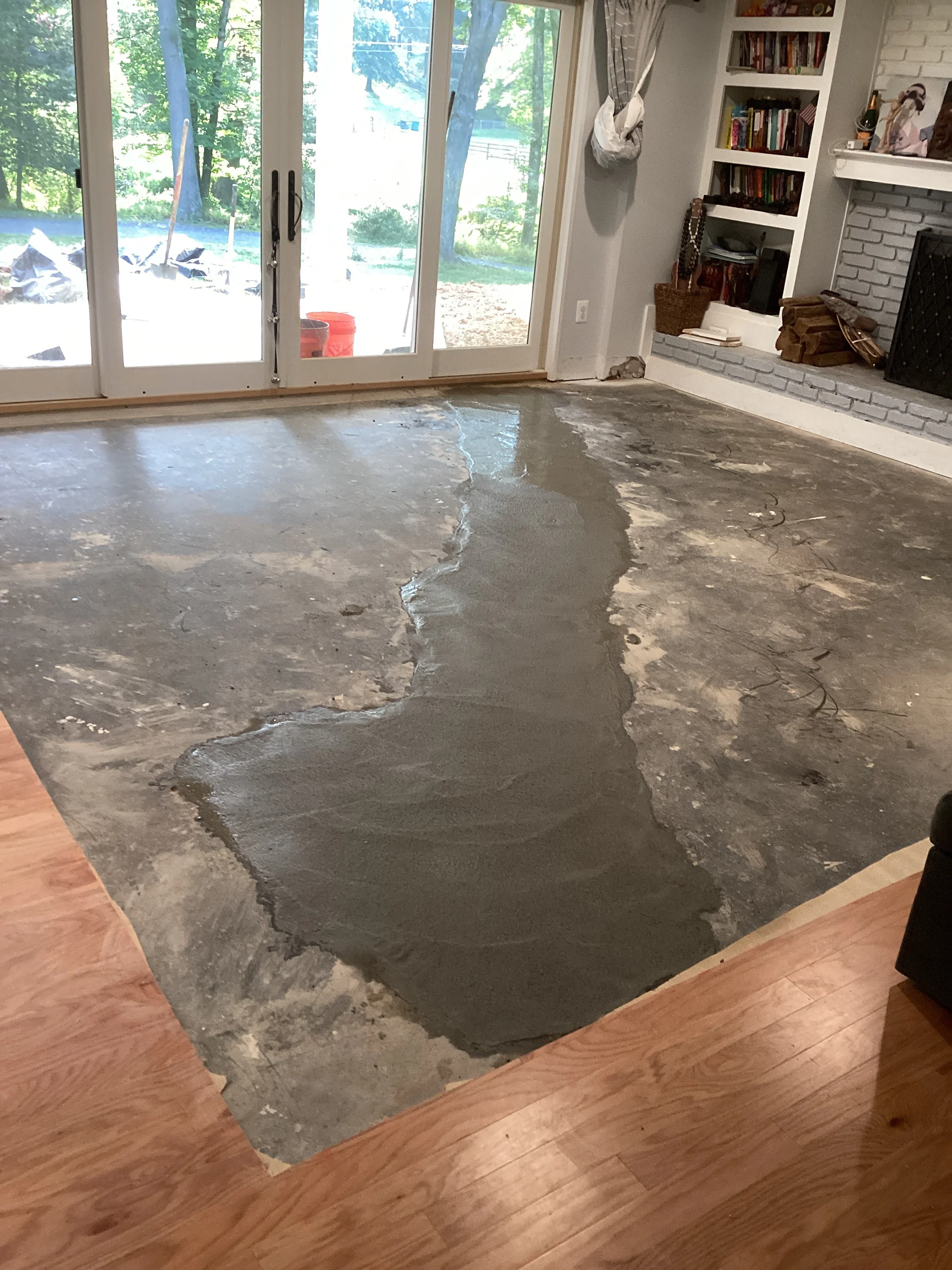 Concrete floor repair in progress showing freshly poured and leveled concrete sections in residential room