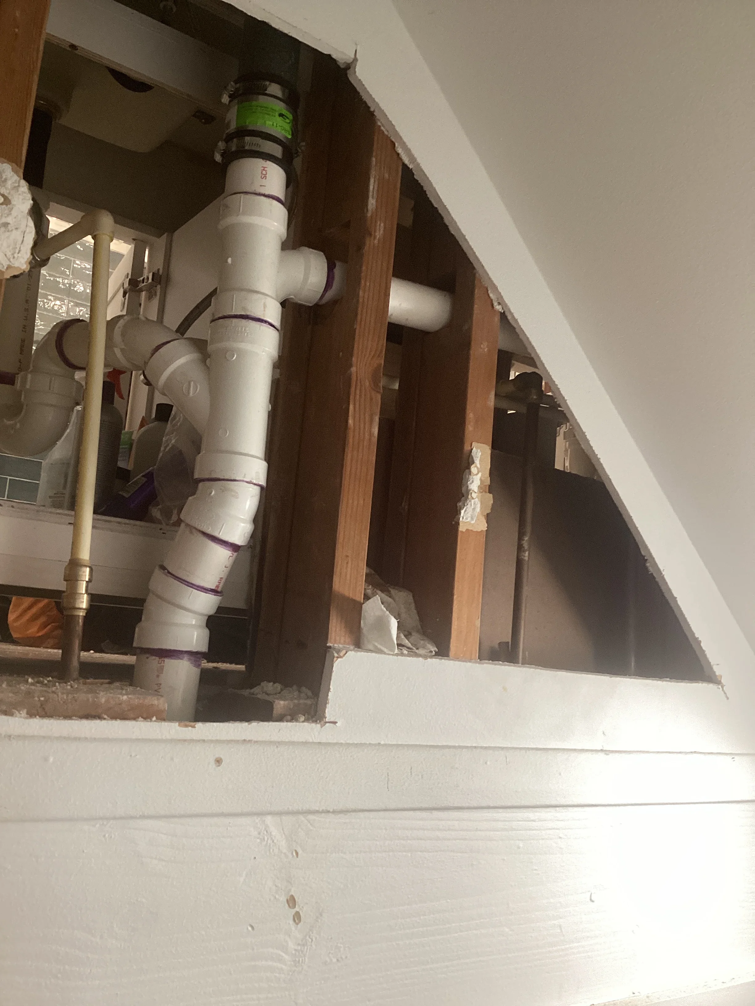 Under-sink plumbing with white PVC pipes, shut-off valves, and drain assembly installed in cabinet