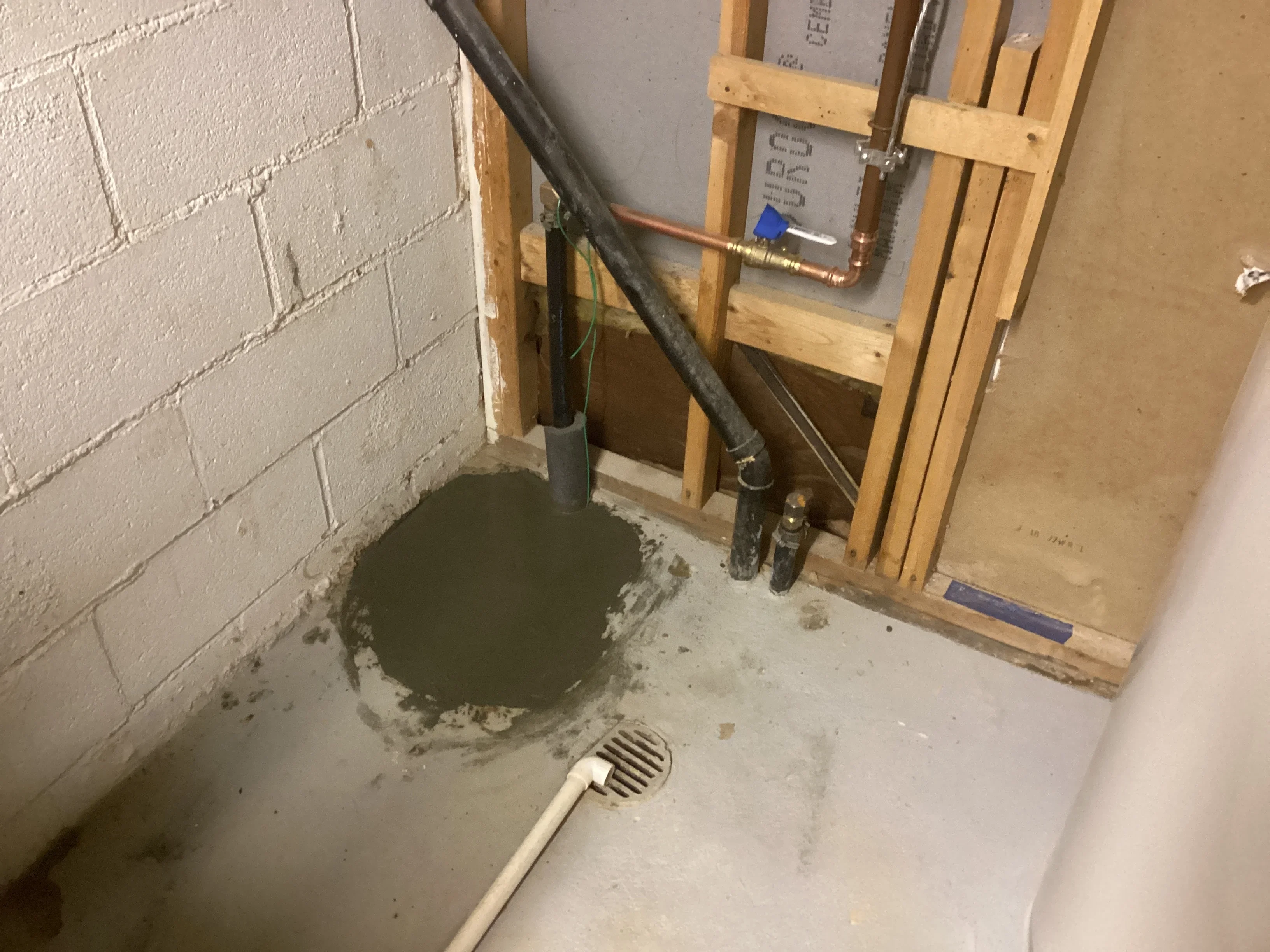 Basement sump pump installation with wooden framing and copper piping connections