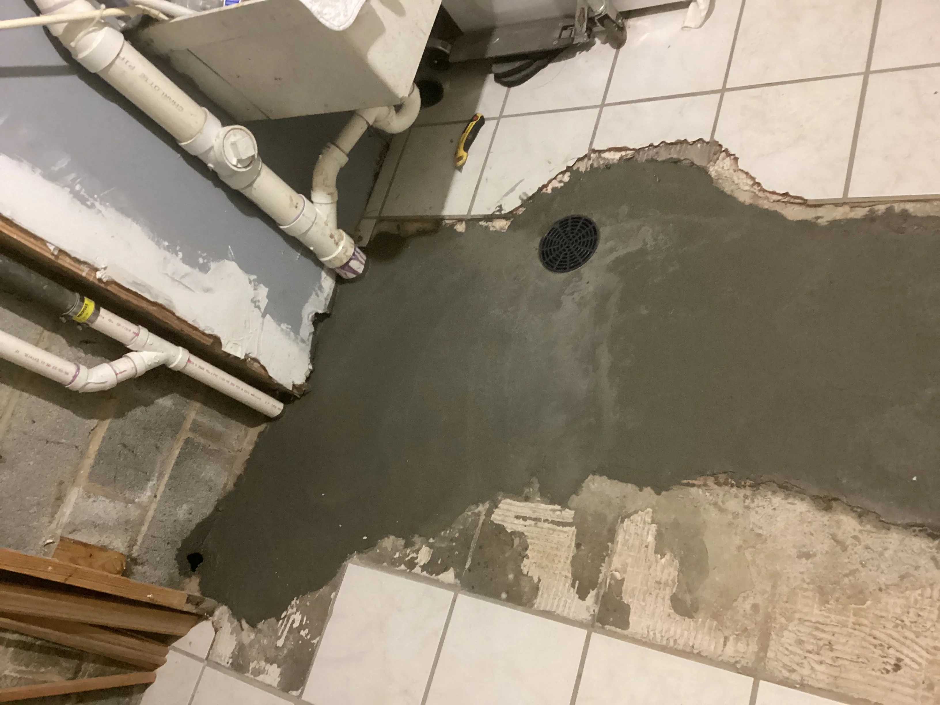 Basement plumbing installation with PVC pipes, drywall patches, and ventilation duct