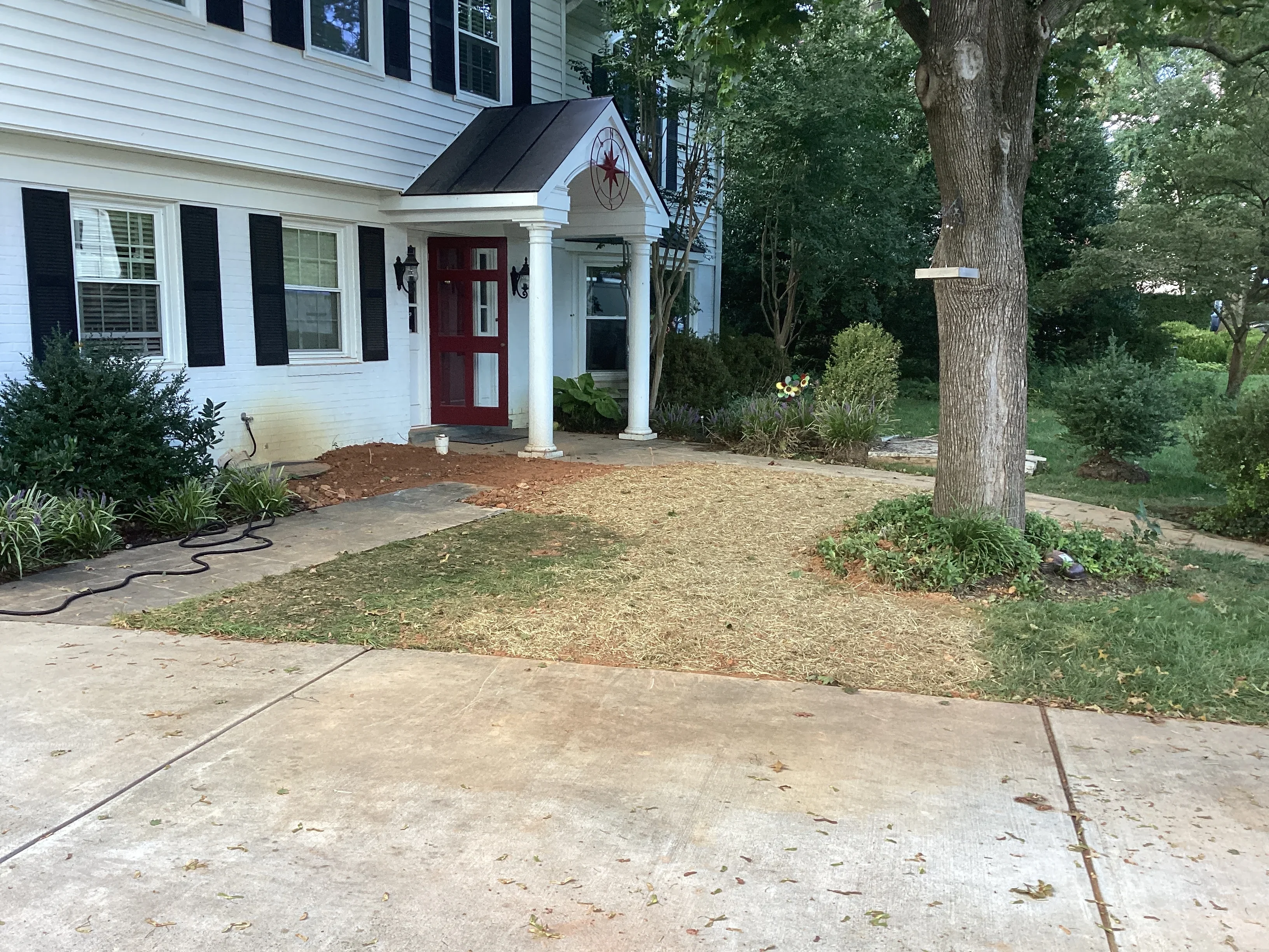 Front yard with new gravel drainage base and landscape grading near white colonial home entrance
