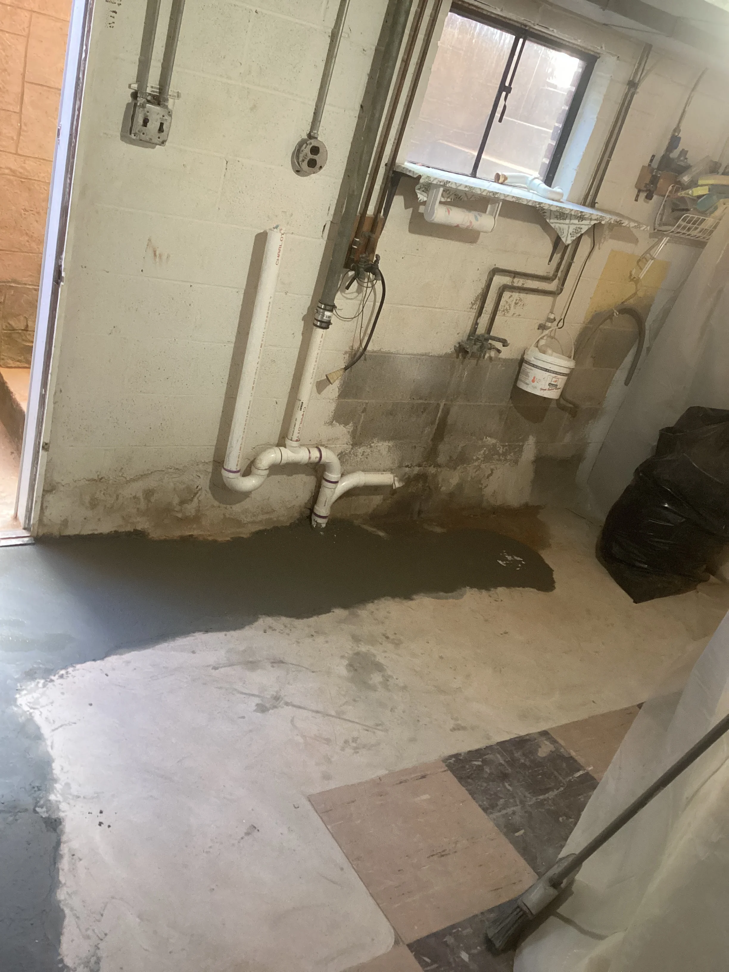 Basement plumbing rough-in with PVC pipes, drain lines, and fixture connections installed
