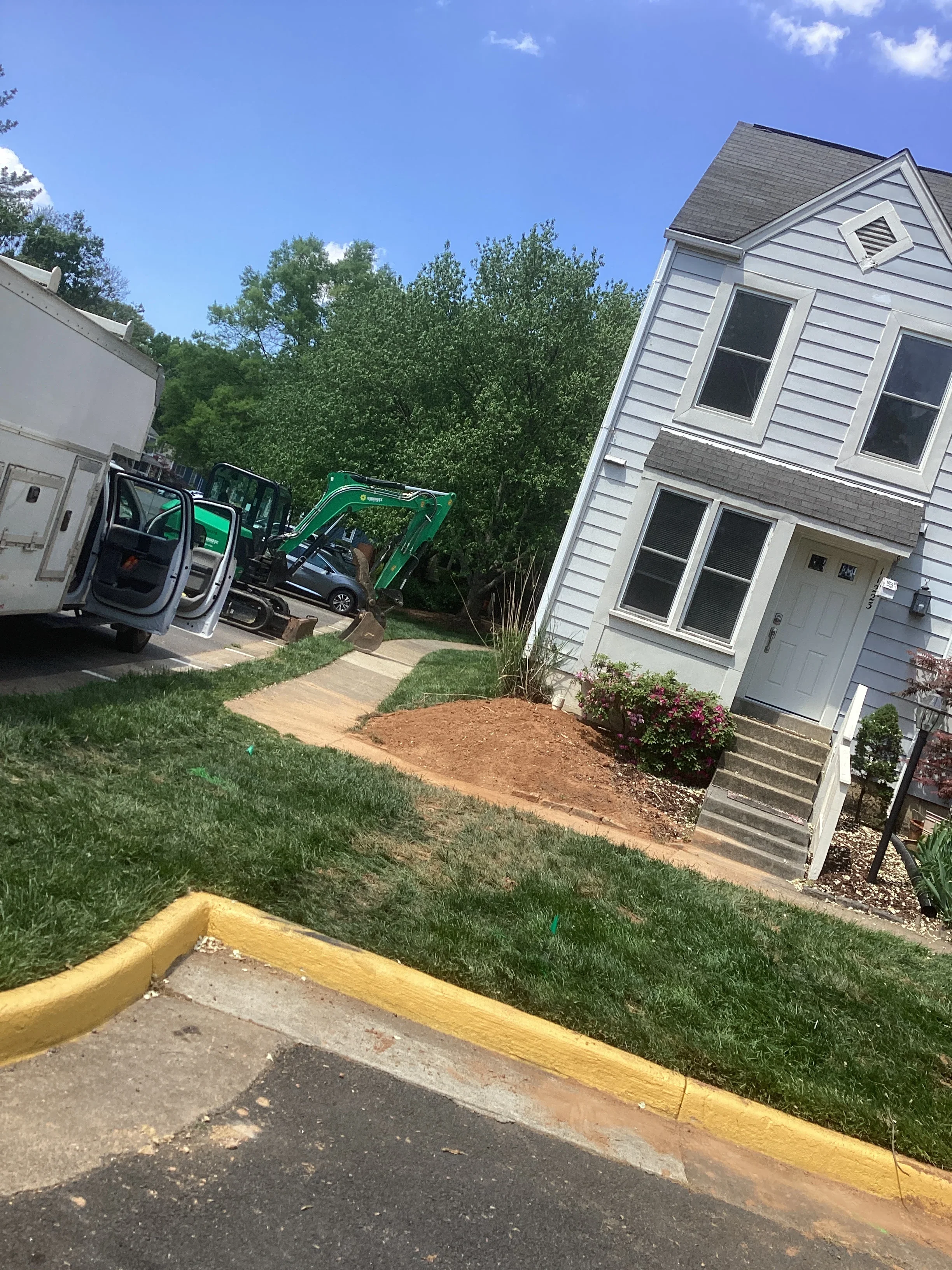 Residential excavation project with green compact excavator and prepared landscape bed